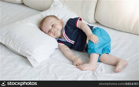 1 year old baby lying on big pillow on bed