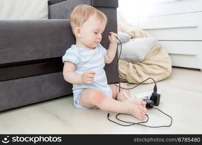 10 months old baby boy pulling cables from electrical extension