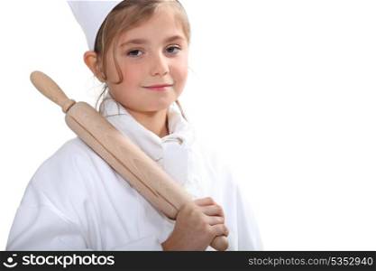 10 years old blonde girl dressed in pastry cooker and taking a rolling pin