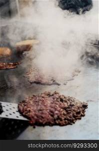 100  beef burgers on the griddle in a cafeteria