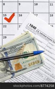1040 Individual Income Tax Return blank with dollar bills, calculator and pen on calendar page with marked 15th April. Tax period concept. IRS Internal Revenue Service. 1040 Individual Income Tax Return blank with dollar bills, calculator and pen on calendar page with marked 15th April