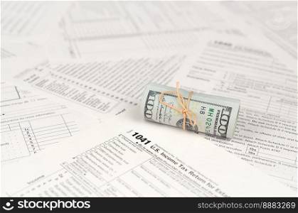 1041 U.S. Income tax return for Estates and Trusts form with roll of american dollar banknotes close up. Concept of tax period in United States. 1041 U.S. Income tax return for Estates and Trusts form with roll of american dollar banknotes