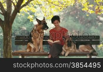 12of15 Young people and pets, portrait of happy hispanic girl at work as dog sitter with alsatian dogs in park, reading book and relaxing