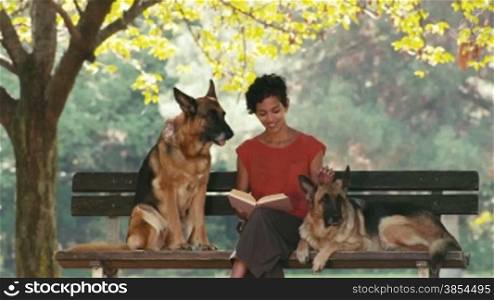 12of15 Young people and pets, portrait of happy hispanic girl at work as dog sitter with alsatian dogs in park, reading book and relaxing