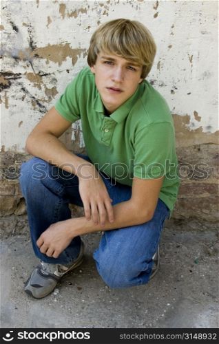 15 year old boy outside against old wall. Blonde hair, blue eyes.