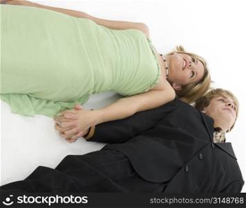 15 year old teen boy and girl in formals holding hands. Laying on white floor.