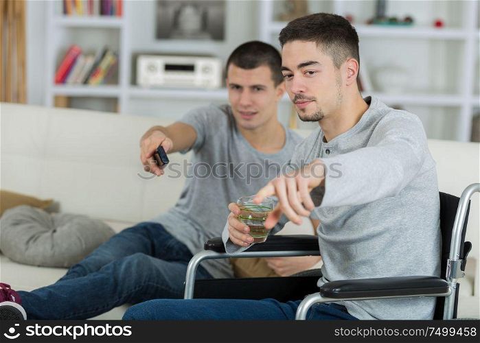 2 friends watching tv at home one is disabled