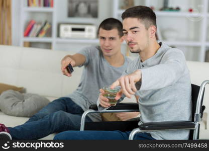 2 friends watching tv at home one is disabled