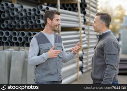 2 male coleagues chatting at pipe factory yard