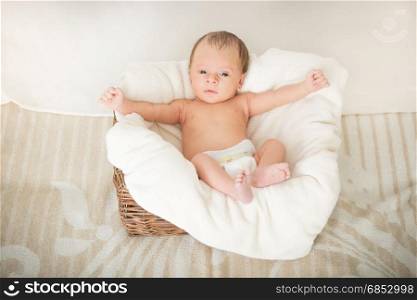 2 month old baby boy sitting in basket covered by blanket