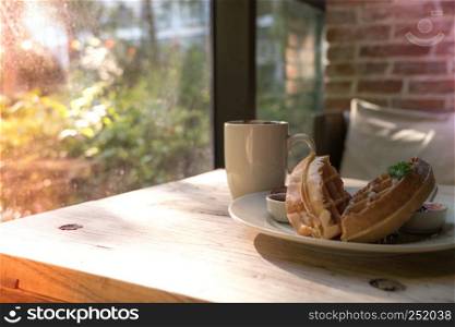 2 pieces of waffle with a white cup of coffee on the wooden table
