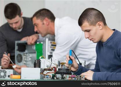 2 teen boys and teacher in electronics class