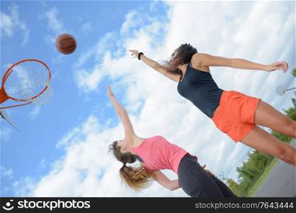 2 women playing basketball outdoors