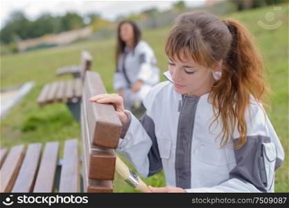 2 women varnishing park benches