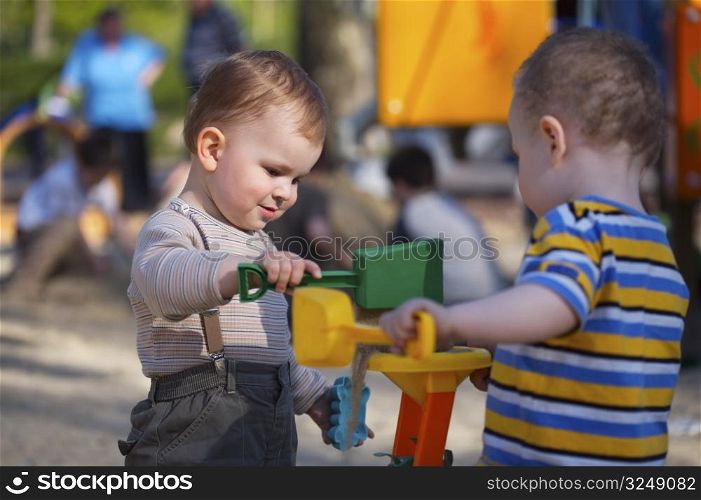 2 years old children are playing together in the sandbox