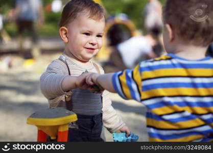 2 years old children are playing together in the sandbox