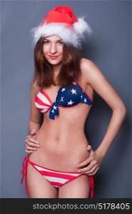 20-25 years old beautiful woman in christmas hat and swimsuit with american flag