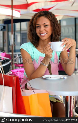 20 years old metis woman is drinking coffee on a terrace, she did shopping before