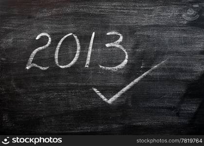 2013 written in chalk on a smudged blackboard,with a tick