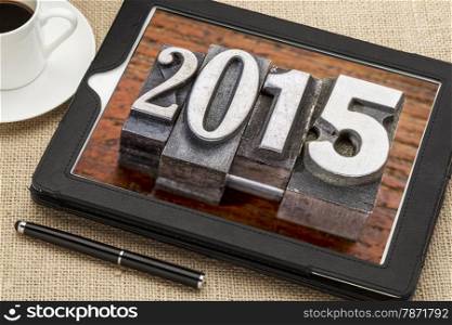 2015 - New Year concept - number in vintage metal type printing blocks on a digital tablet with a cup of coffee