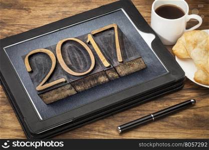 2017 - New Year concept - number in vintage wood type printing blocks on a digital tablet with a cup of coffee