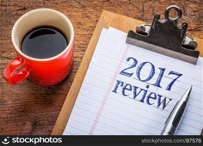 2017 year review on clipboard and coffee against grunge wood desk