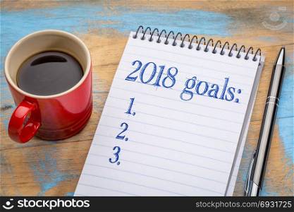 2018 goalslist in notebook a spiral notebook with a cup of coffee, goal setting and resolutions concept