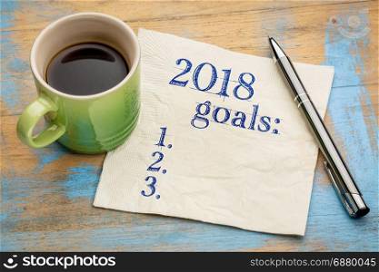 2018 year goals list on a napkin on a wood table with a cup of coffee