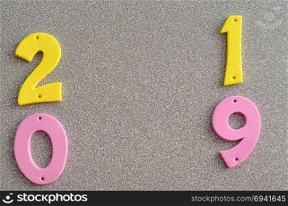 2019 in pink and yellow numbers on a silver background