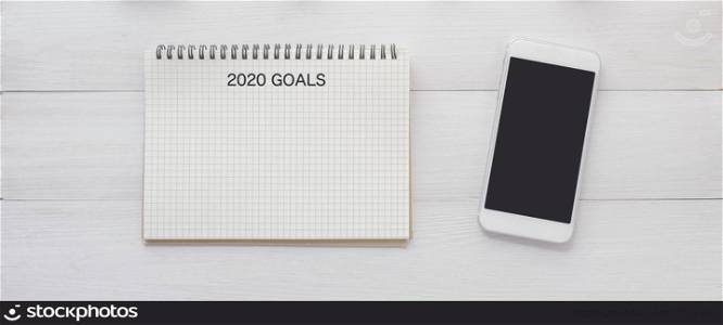 2020 goals on blank note paper and smart phone with blank screen on white marble background, 2020 new year aim to success in business background, mock up