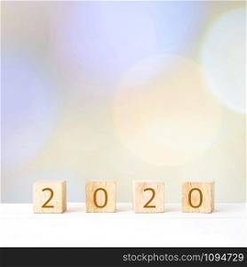 2020 happy new year on wooden block cubes over blur bokeh background, banner with copy space for text, new year greeting card template poster, wallpaper, backdrop