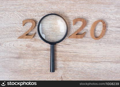 2020 Happy New year with Businessman holding glass magnifying and wooden number on table. New Start, Vision, Resolution, Strategy, Goals, Mission and Search Engine Optimization concept