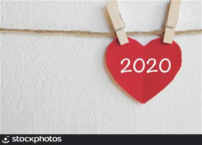 2020 new year greeting card template, Red fabric heart with 2019 word hanging on white wall background with copy space