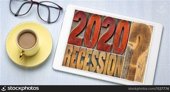 2020 recession? Word abstract in vintage letterpress wood type on a digital tablet with coffee. Economy and business forecast, expectation and speculation concept.
