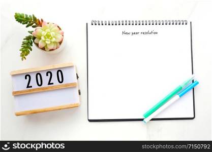 2020 resolution on blank notebook paper over white marble background, 2020 new year mock up, template, flat lay