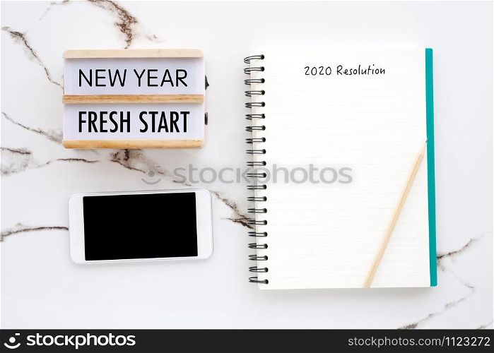 2020 resolution on blank notebook paper, smart phone with blank screen on white marble background, 2020 new year mock up, template, flat lay