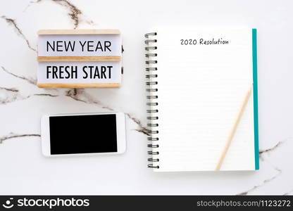 2020 resolution on blank notebook paper, smart phone with blank screen on white marble background, 2020 new year mock up, template, flat lay