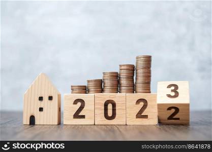 2022 flipping to 2023 year block with house model and Coins stack. real estate, Home loan, tax, investment, mortgage, financial, savings and New Year Resolution concepts