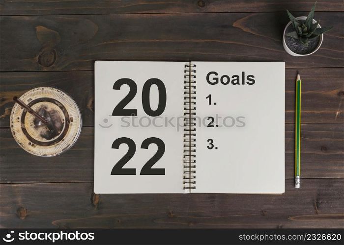 2022 goals text on notepad with coffee cup and pen on wooden desk