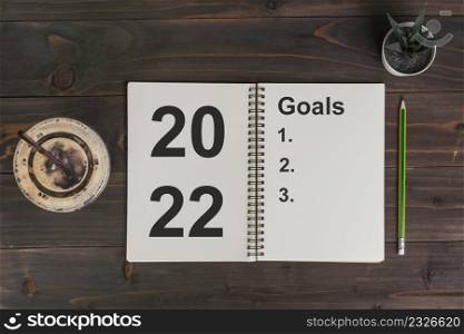 2022 goals text on notepad with coffee cup and pen on wooden desk