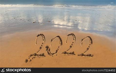 2022 hand writing on the sand to the beach with ocean background