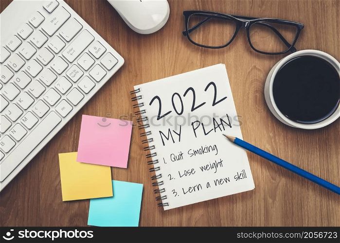 2022 Happy New Year Resolution Goal List and Plans Setting - Business office desk with notebook written about plan listing of new year goals and resolutions setting. Change and determination concept.