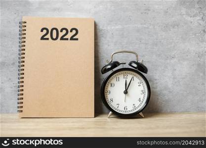 2022 Happy New Year with blank notebook, black retro alarm clock and wooden number. countdown, Resolution, Goals, Plan, Action and Mission Concept