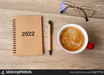 2022 notebook and coffee cup on wood table, Top view and copy space. Xmas, Happy New Year, Goals, Resolution, To do list, Strategy and Plan concept