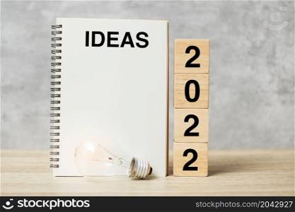 2022 text wood cube blocks and IDEAS word with lightbulb on table. New Year New Ideas, Creative, Innovation, Imagination, inspiration, Resolution, Strategy and goal concept