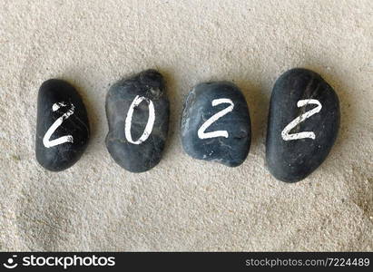 2022 written on black pebbles on the sand