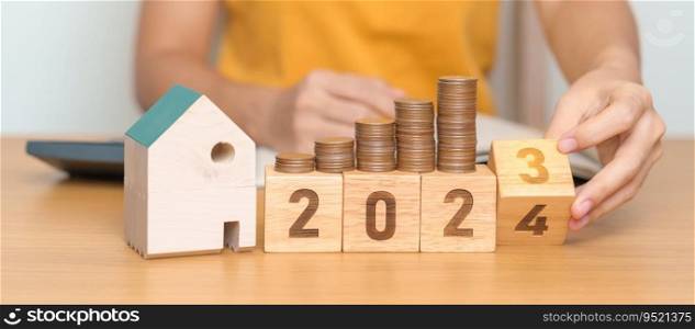 2023 flipping to 2024 year block with house model and Coins stack. real estate, Home loan, tax, investment, mortgage, financial, savings and New Year Resolution concepts