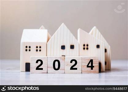 2024 Happy New Year with house model on table wooden background. Banking, real estate, investment, financial, savings and New Year Resolution concepts