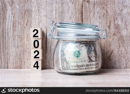 2024 Happy New Year with US dollar money glass American on wood table background. business, investment, retirement planning, finance, Saving and New Year Resolution concepts