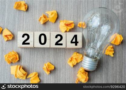 2024 text wood cube blocks and crumbled paper with lightbulb on wooden table background. New Year New Ideas, Creative, Innovation, Imagination, inspiration, Resolution, Strategy and goal concept